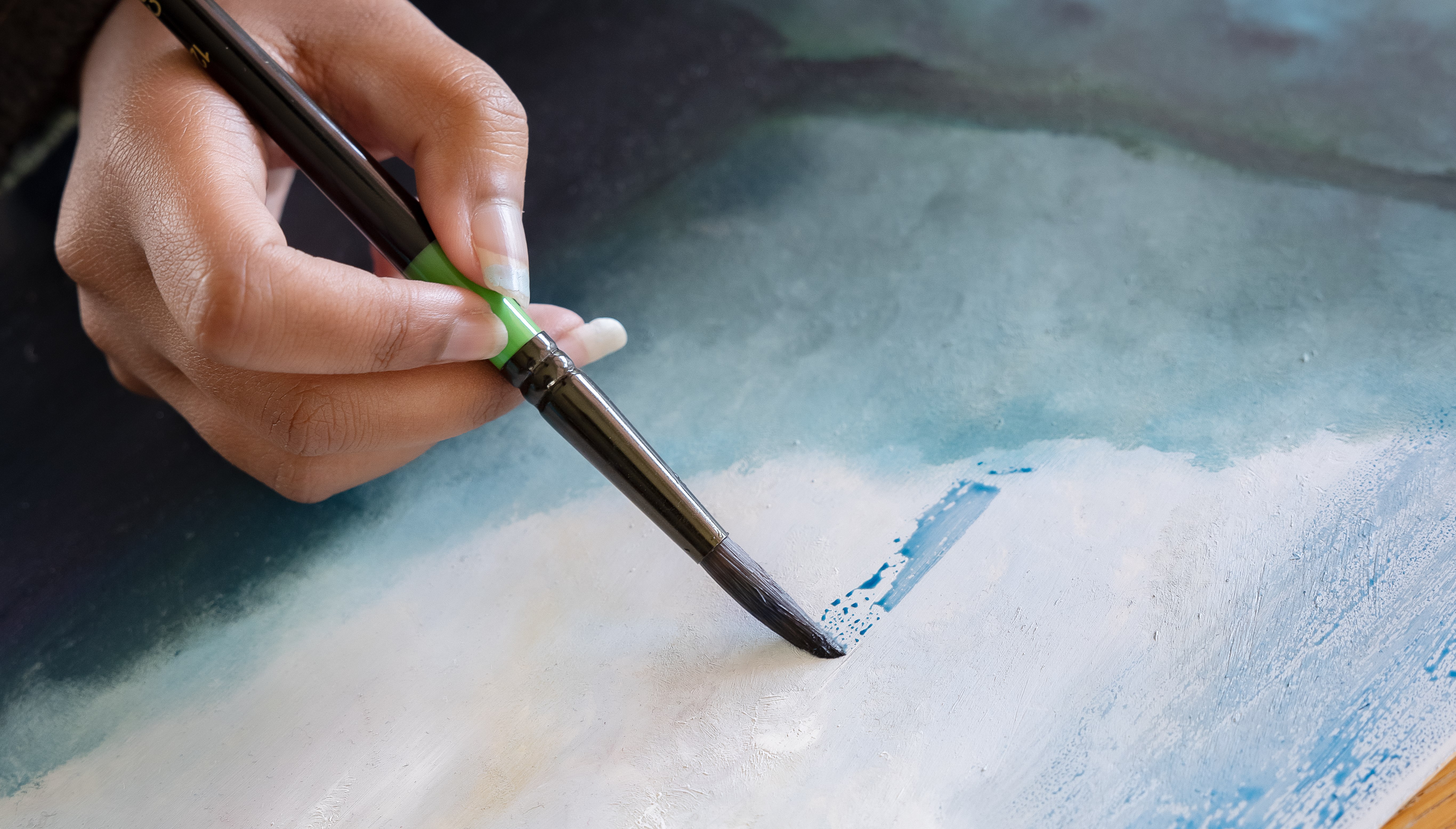 En hand håller i en pensel och målar