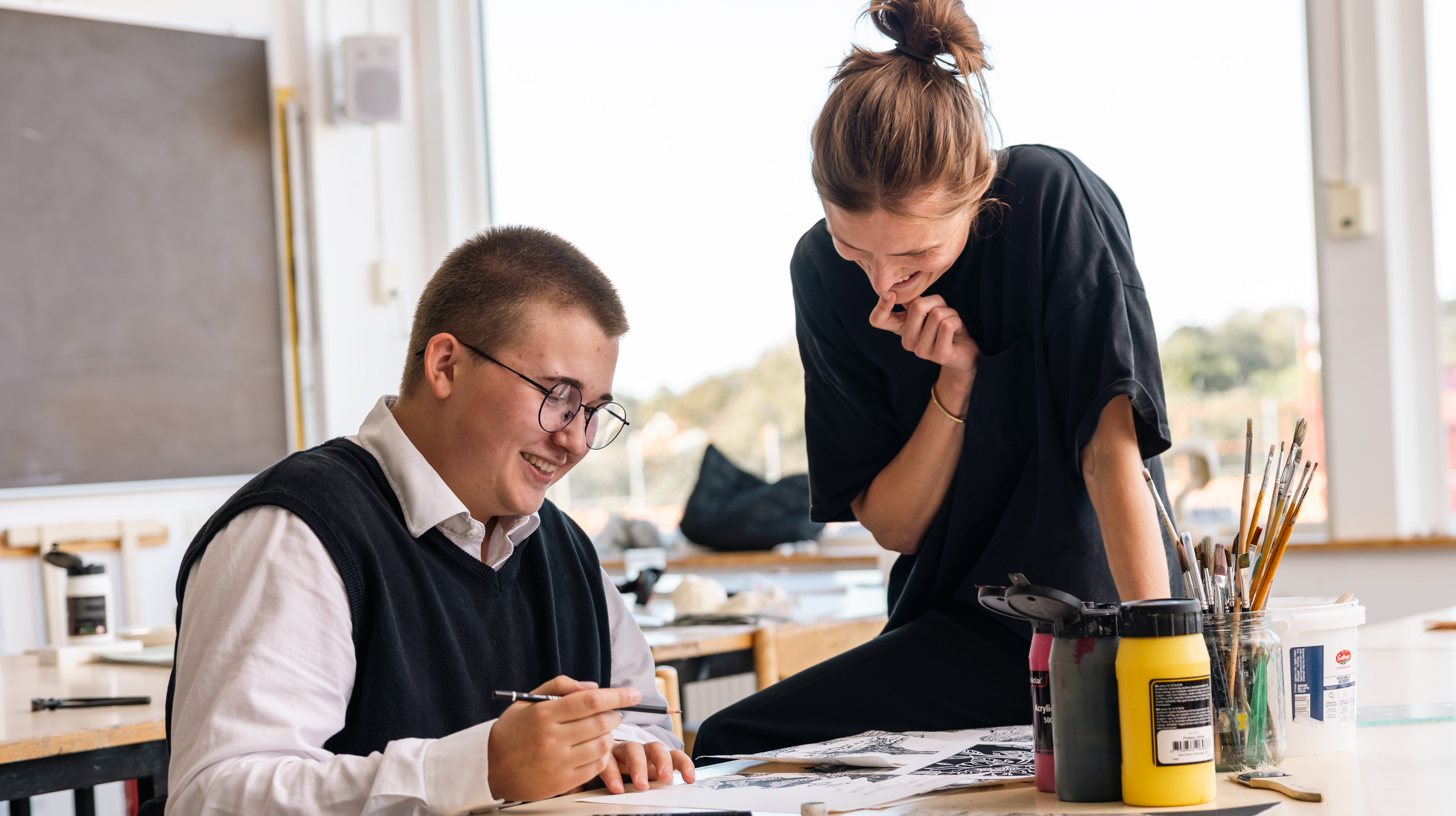 Två leende personer i ett klassrum.